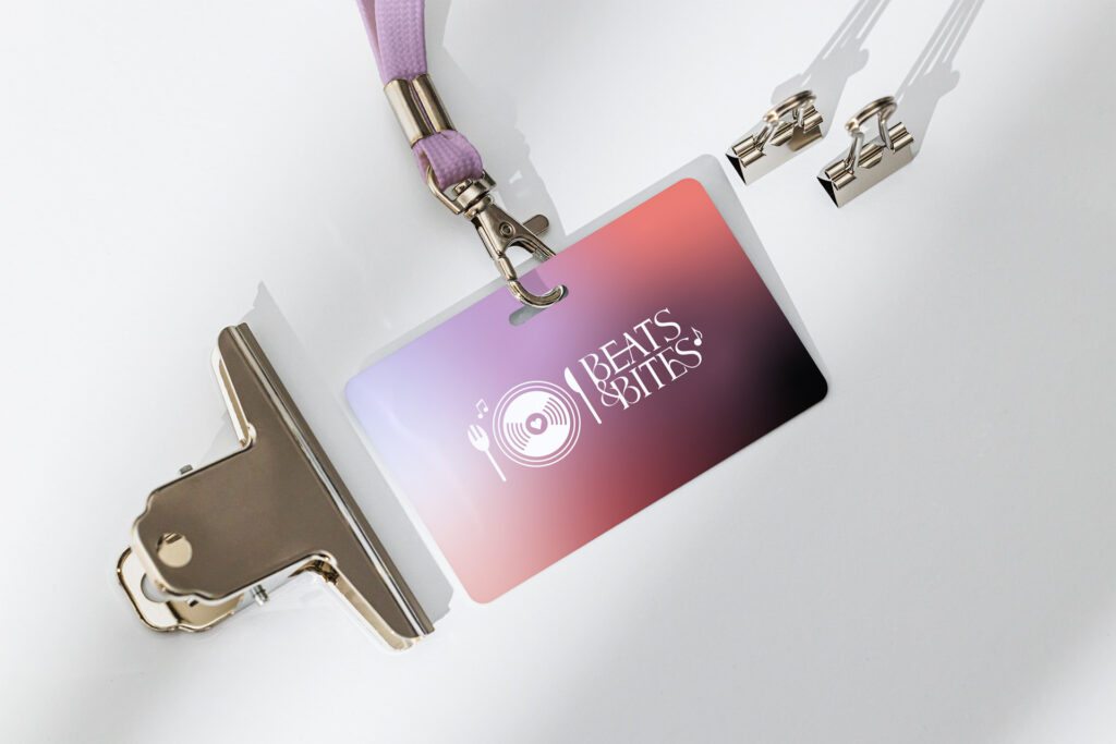 ID-Karte eines Festivals mit der Aufschrift "Beats & Bites" auf einem Farbverlauf aus rosa und lila Tönen.